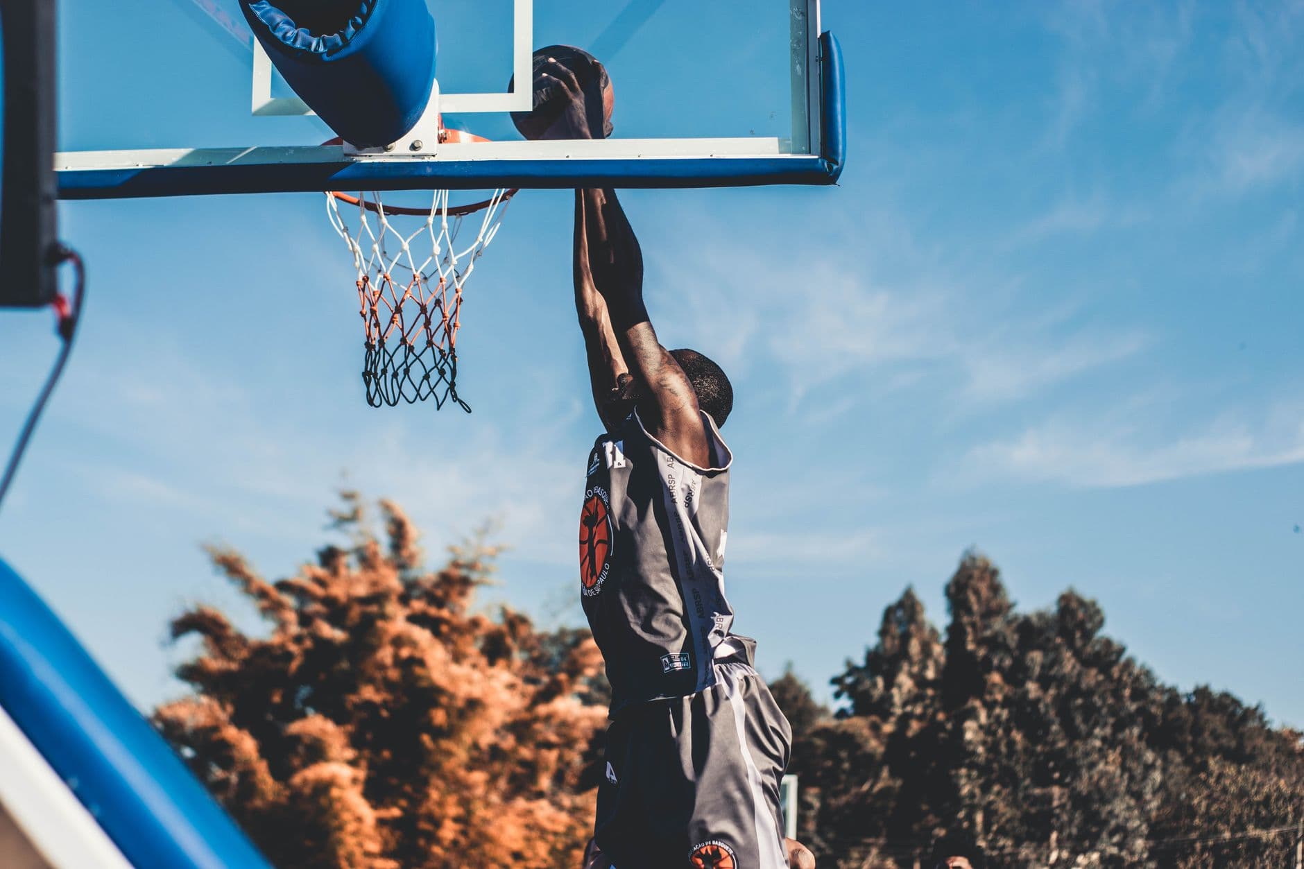 A basketball player rising to dunk against an open sky