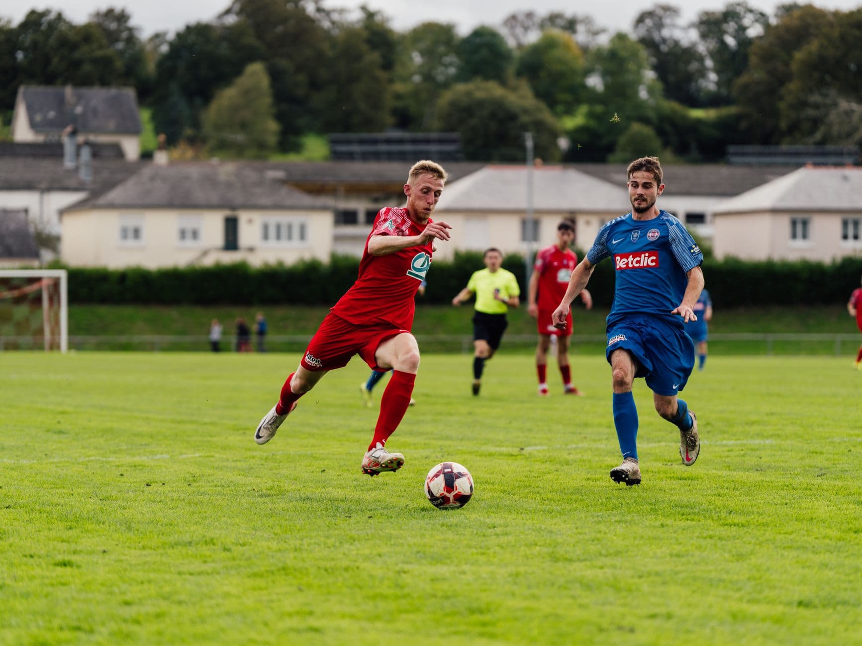 Two footballers contesting the ball on a grass pitch