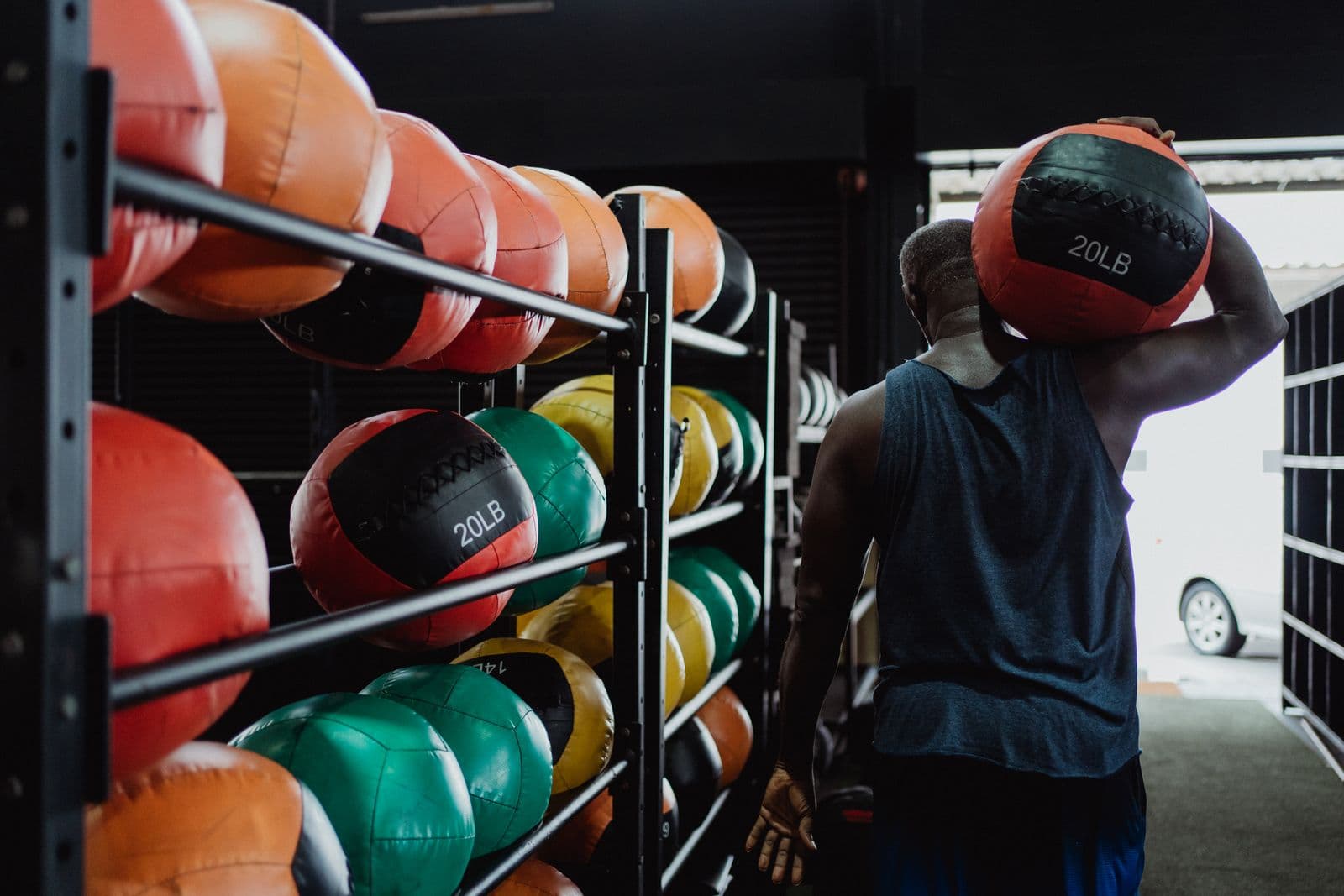An athlete carrying a medicine ball past a rack of them