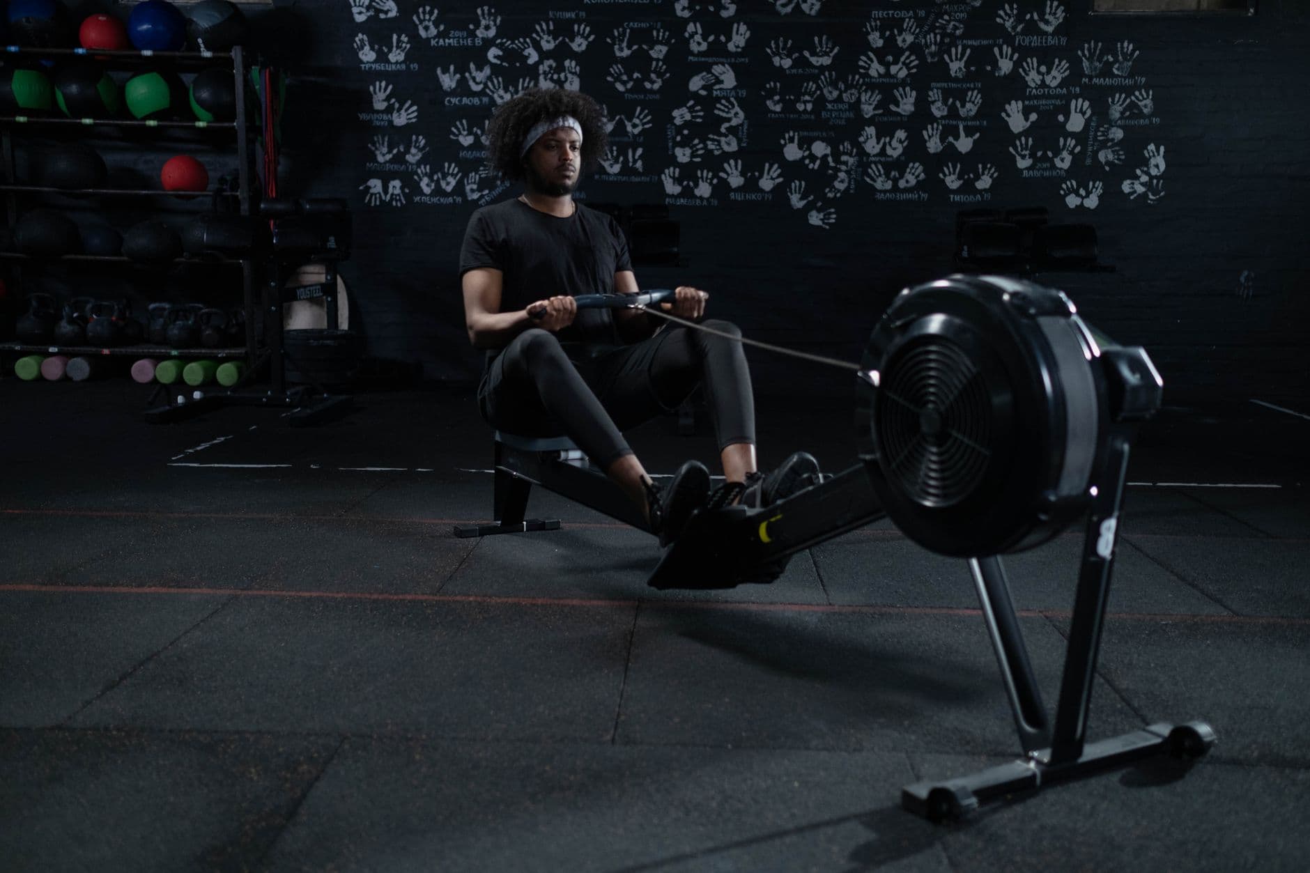 An athlete pulling on an indoor rowing machine in a dark gym