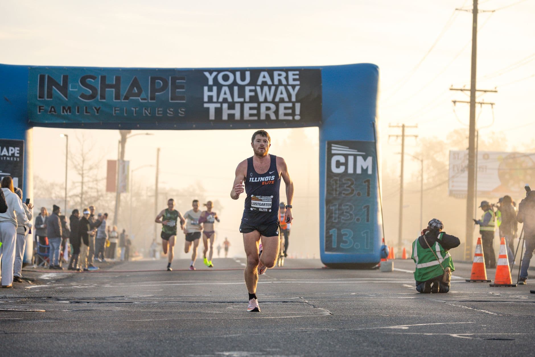 A runner passing a race arch in early morning light