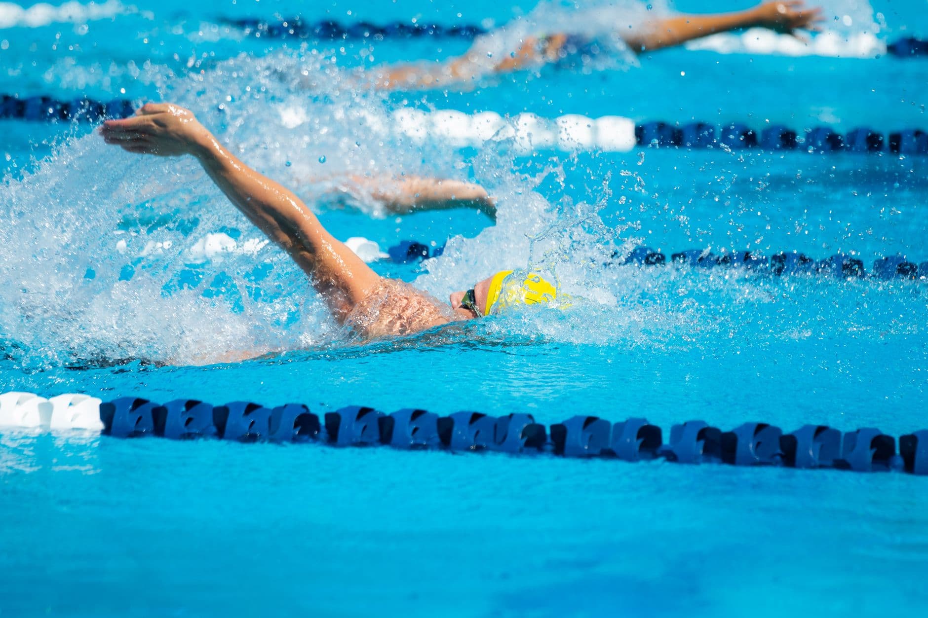 A swimmer mid-stroke in a marked pool lane