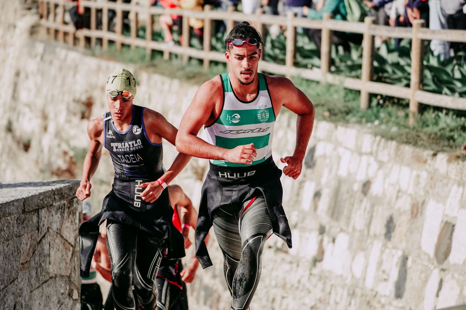 Triathletes running out of the water in wetsuits