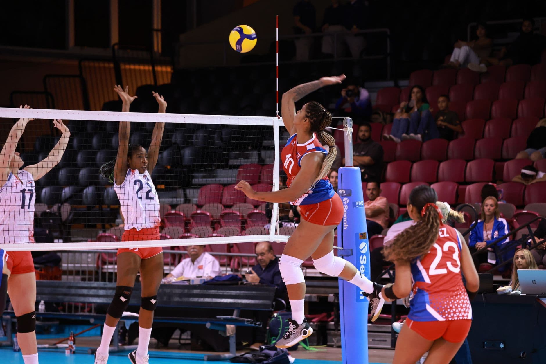 Players contesting the ball at the net in an indoor volleyball match
