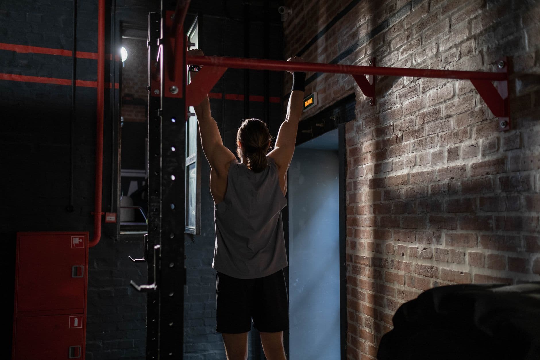 Pull-ups on a bar in a dark gym